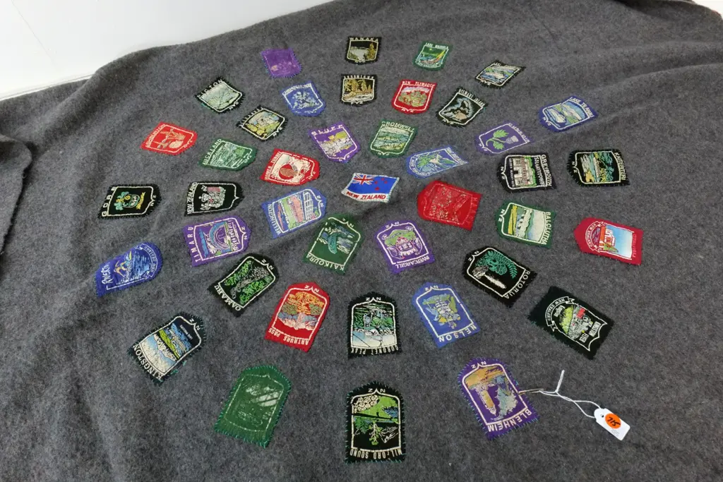 grey woollen blanket with approx. 30 assorted New Zealand place names badges Image 1++