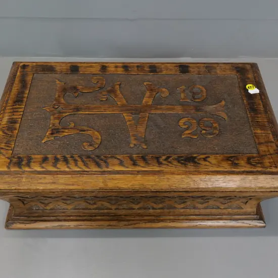 solid oak box with hinged lid, carved motifs and "1929" on lid H-150 W-430 D-260