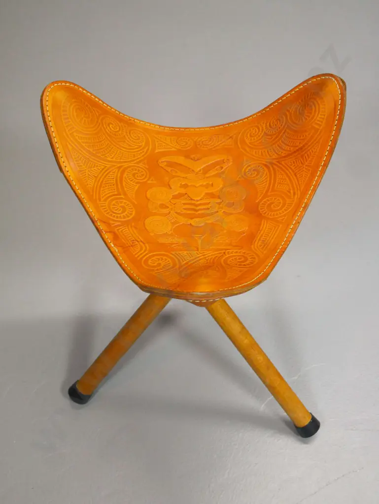 collapsible tripod stool with Maori themed tooled leather seat - stitching coming loose on one corner H470 W-370 Image 1++