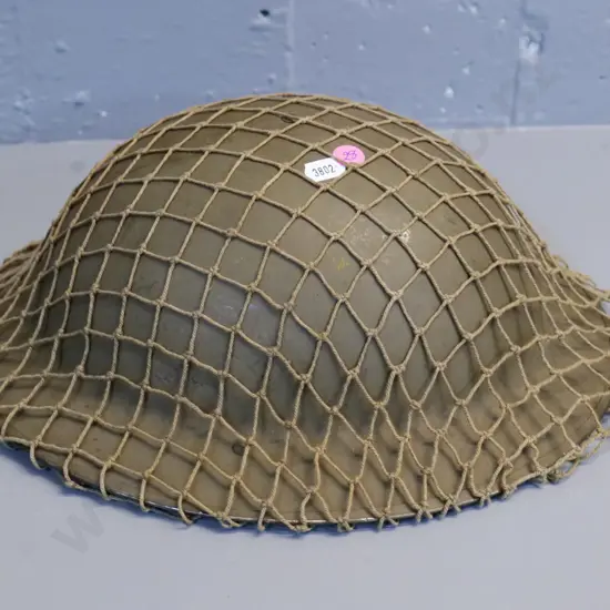 metal WWII era military helmet with leather fittings, netting cover