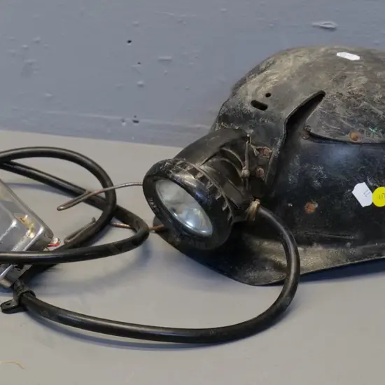 black fibre miner's helmet with lamp cord and fitting - light housing marked Oldham & Son Manchester . Wear and tear
