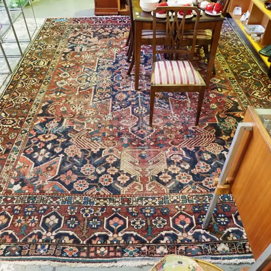 large Persian style hand-knotted wool floor rug - considerable wear to centre area L3780 W3000