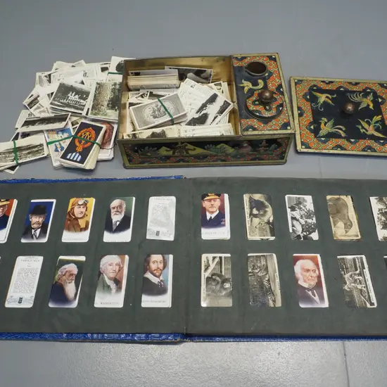 Three Castles cigarette card album and numerous loose cards in a vintage printed tin writing box