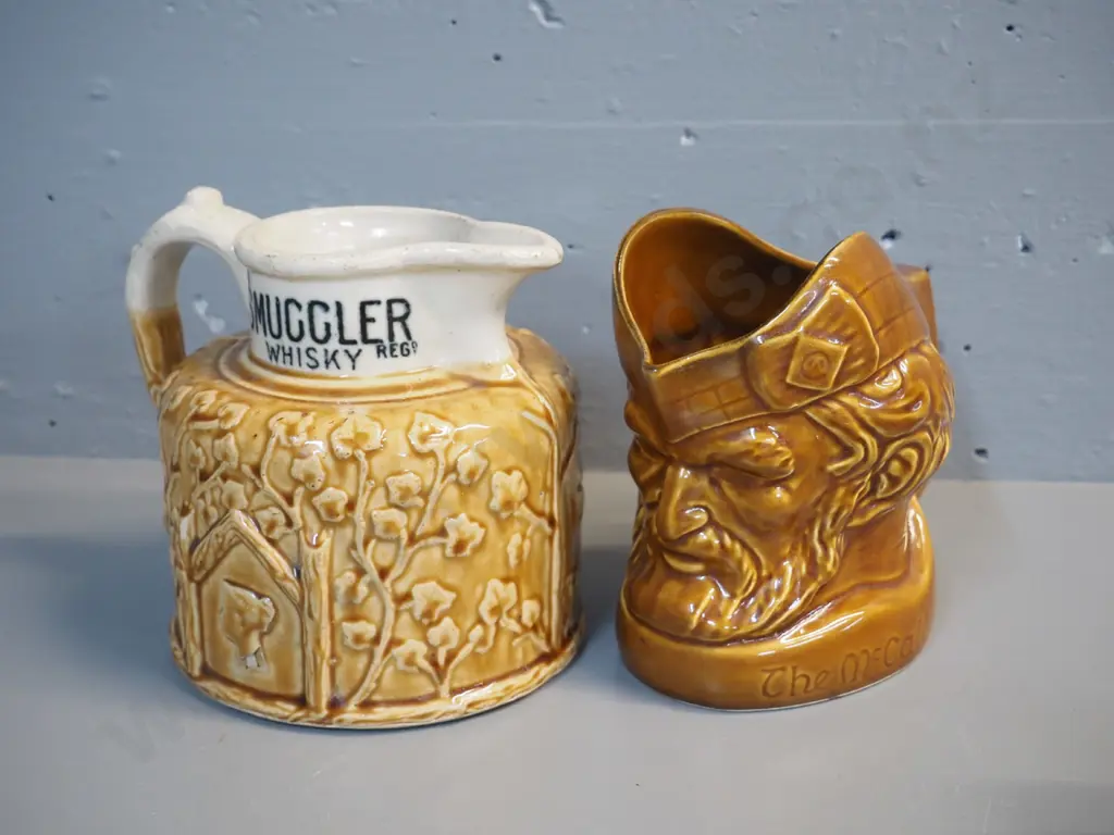 2 whisky jugs: Old Smuggler w/Port Dundas stamp on base, has chip off relief decoration H170 W200, and McCallum Image 1++