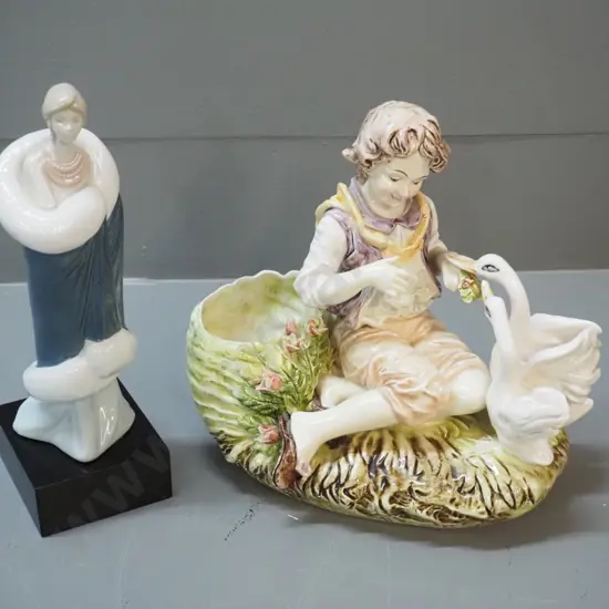 2 figurines - boy feeding geese , no maker's mark, and a woman figure marked Compliments of Marco Giner 1987, H-230