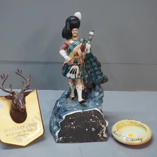 whisky items - Dewar's piper figure with finish wear H-350, Maclay-Duff stag's head plaque, DCL ashtray