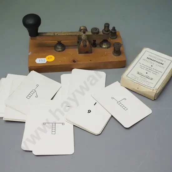 vintage morse key on wooden base and a pack of semaphore signal training cards